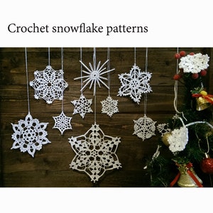May include: A collection of ten white crocheted snowflake decorations hanging from a wooden wall. The snowflakes are various sizes and designs, with some featuring intricate patterns. The snowflakes are hanging from a rustic wooden wall.