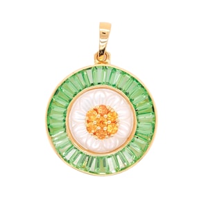 May include: A gold pendant with a floral design. The pendant features a white center with a cluster of orange gems, surrounded by a ring of green baguette-cut stones. The outer edge is gold, and the pendant has a gold bail.
