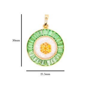 May include: A gold-toned pendant with a daisy design. The pendant features a white center with orange accents, surrounded by a ring of green baguette-cut stones. The pendant is 30mm in length and 21.5mm in width.