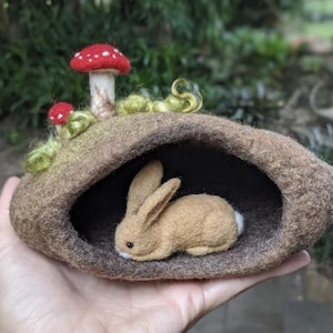 Toca de feltro na floresta com coelhos e cogumelos.