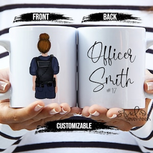 Peut inclure: Mug en céramique blanche avec une illustration de dessin animé d'un policier sur le devant et le texte "Officer Smith #17" au dos.