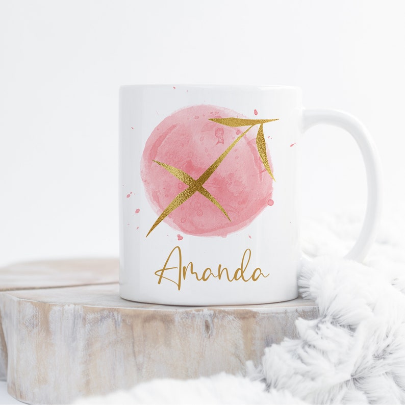 May include: White ceramic mug with a pink watercolor circle and gold Sagittarius zodiac symbol. The name "Amanda" is written in gold lettering below the symbol.
