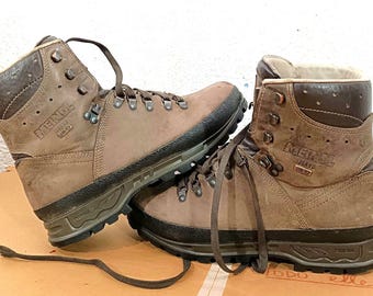 May include: A pair of brown hiking boots with dark brown accents. The boots have a high-top design with laces, metal eyelets, and a durable sole. The brand name "Meindl" is visible on the side of the boots. These boots are designed for outdoor activities.
