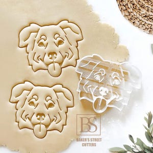 May include: Two impressions of a dog face cookie cutter in rolled dough and one white plastic dog face cookie cutter. The cutter features a detailed canine head with floppy ears and a tongue sticking out. The text BS BAKER'S STREET CUTTERS is visible.