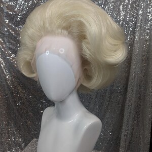 May include: A blonde wig with a bouffant style. The wig is on a white mannequin head.