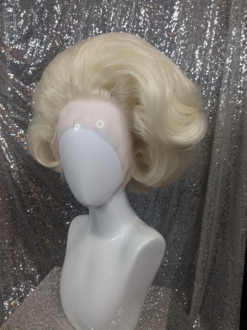 May include: A blonde wig with a bouffant style. The wig is on a white mannequin head.
