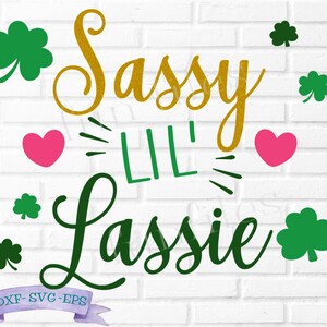 May include: Sassy Lil' Lassie text with green shamrocks and pink hearts on a white brick background.