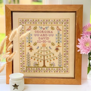 May include: A framed cross-stitch sampler with a floral design and the names Georgina and David, along with the date 22-05-16.