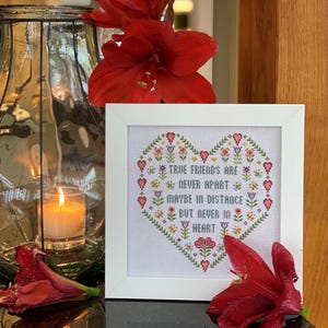 May include: White framed cross-stitch embroidery featuring a heart-shaped design. The heart is filled with colourful flowers and the text "True friends are never apart maybe in distance but never in heart".