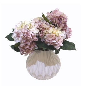May include: A bouquet of faux hydrangeas in shades of pink, lavender, and cream, with green leaves, arranged in a two-toned white and beige textured vase. A decorative floral arrangement for home decor.