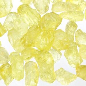 Puede incluir: Una colecci&oacute;n de cristales de color amarillo, transl&uacute;cidos y de corte tosco. Los cristales son de varios tama&ntilde;os y formas, y tienen un aspecto natural sin pulir.