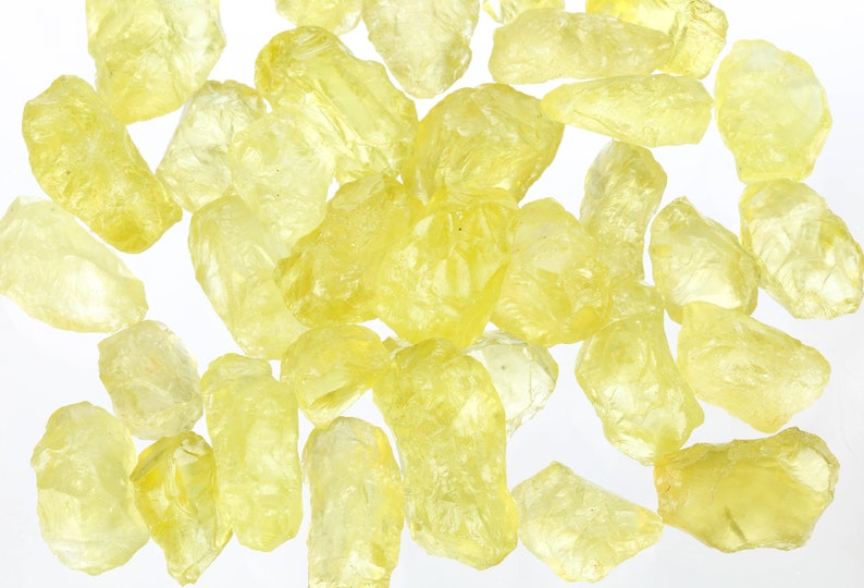 Puede incluir: Una colecci&oacute;n de cristales de color amarillo, transl&uacute;cidos y de corte tosco. Los cristales son de varios tama&ntilde;os y formas, y tienen un aspecto natural sin pulir.
