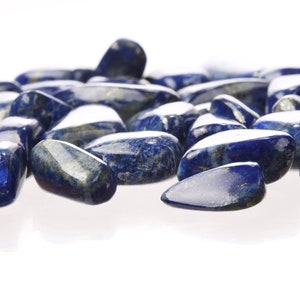 May include: A collection of smooth, polished, dark blue lapis lazuli stones. The stones are tumbled and have a natural, irregular shape.