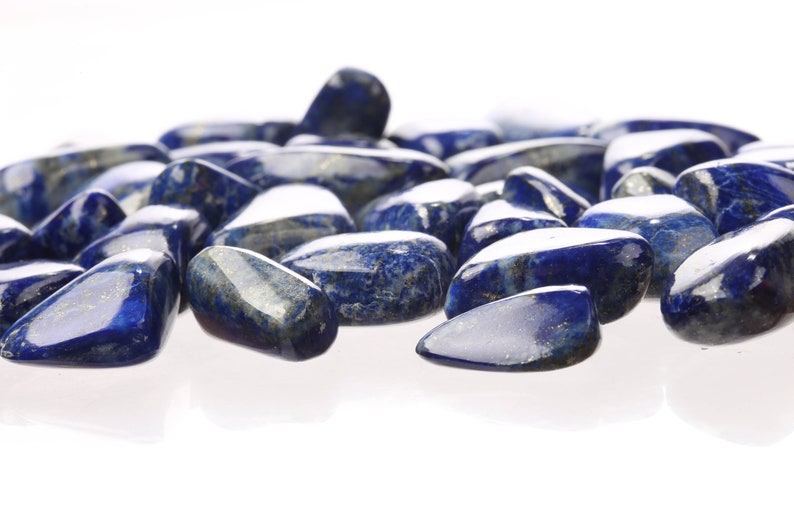 May include: A collection of smooth, polished, dark blue lapis lazuli stones. The stones are tumbled and have a natural, irregular shape.