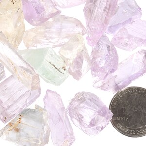 May include: A collection of pale pink, green, and white crystal chunks, some with a slight shimmer, next to a US quarter for scale.