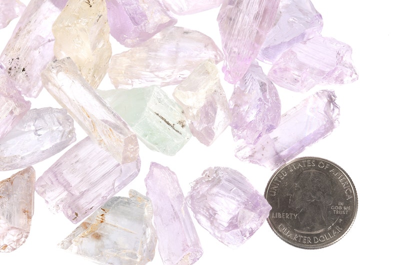 May include: A collection of pale pink, green, and white crystal chunks, some with a slight shimmer, next to a US quarter for scale.