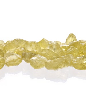 Pu&ograve; includere: Un mucchio di cristalli di citrino gialli traslucidi, alcuni con una leggera sfumatura dorata, su uno sfondo bianco.