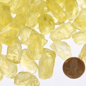 Pu&ograve; includere: Una collezione di cristalli di citrino giallo grezzi, di dimensioni che vanno da piccole a medie. I cristalli sono traslucidi e hanno un colore giallo chiaro. Un centesimo &egrave; incluso per la scala.