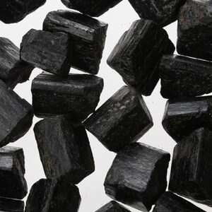 May include: A collection of black tourmaline crystals, also known as schorl, with a rough, natural finish. The crystals are various sizes and shapes, with some showing striations.