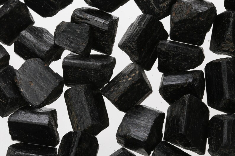 May include: A collection of black tourmaline crystals, also known as schorl, with a rough, natural finish. The crystals are various sizes and shapes, with some showing striations.