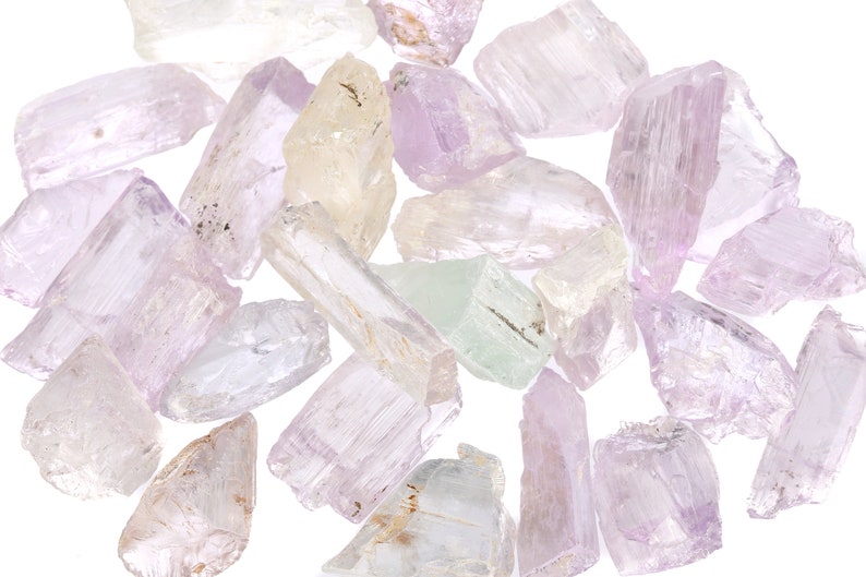 May include: A collection of pale pink, white, and green gemstone crystals. The crystals are rough and have a natural, unpolished look.