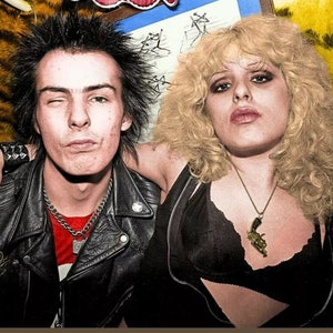 Pode incluir: Uma fotografia a preto e branco de um homem e uma mulher com penteados punk rock. O homem est&aacute; a usar uma jaqueta de couro preta com uma camisa vermelha por baixo. A mulher est&aacute; a usar um top preto com um colar de ouro com um pingente de pistola. Ambos est&atilde;o a olhar para a c&acirc;mara.