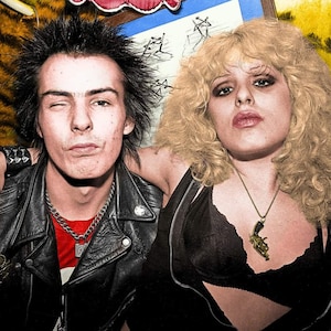 May include: A black and white photo of a couple. The man has short, spiky black hair and is wearing a black leather jacket, a red shirt, and a silver chain necklace. The woman has long, blonde hair and is wearing a black bra and a gold necklace with a gun pendant.
