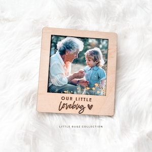 May include: A wooden photo frame with a picture of an older woman and a young child. The frame has the text "Our little lovebug" carved into the wood.