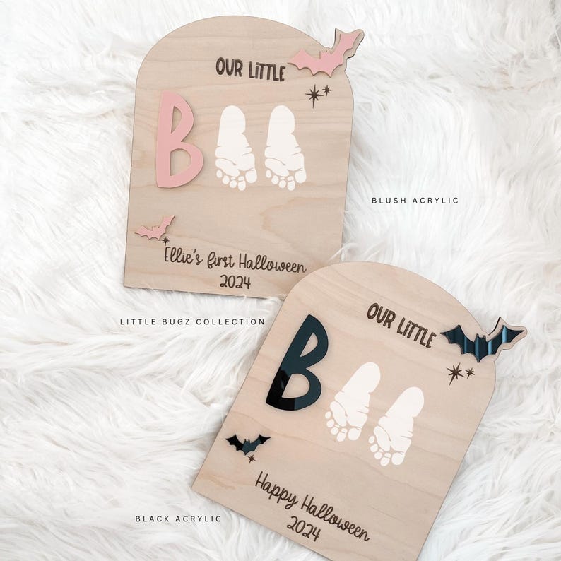 May include: Two wooden Halloween signs with the text "Our Little BOO" and footprints. The top sign is pink and says "Ellie's first Halloween 2024". The bottom sign is natural wood and says "Happy Halloween 2024".