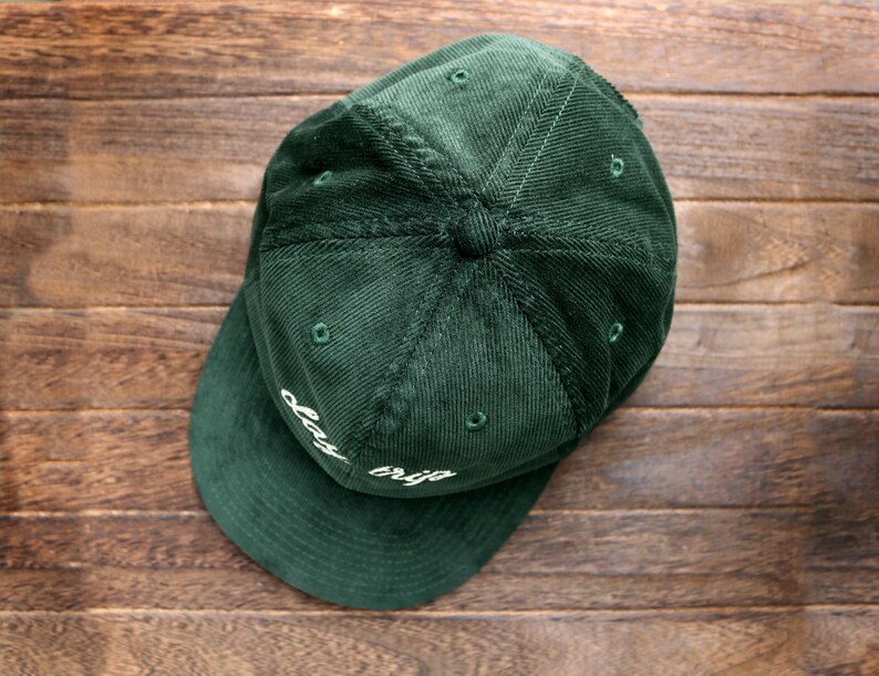 May include: A dark green corduroy baseball cap with a white embroidered design that says "day trip".