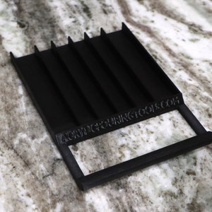 Peut inclure: Plateau en plastique noir avec six fentes et une poignée. Le plateau porte l'inscription "precisioncuttingtools.com" sur le côté.