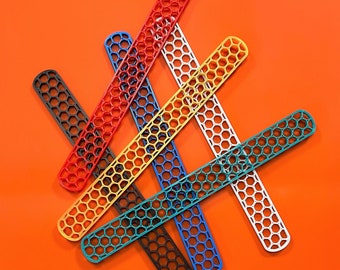 Może przedstawiać: Sześć kolorowych plastikowych linijek z wzorem plastra miodu. Linijki są ułożone w kształcie krzyża na pomarańczowym tle.