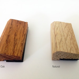 May include: Two wood samples, one stained dark oak and the other natural, with a black backing.