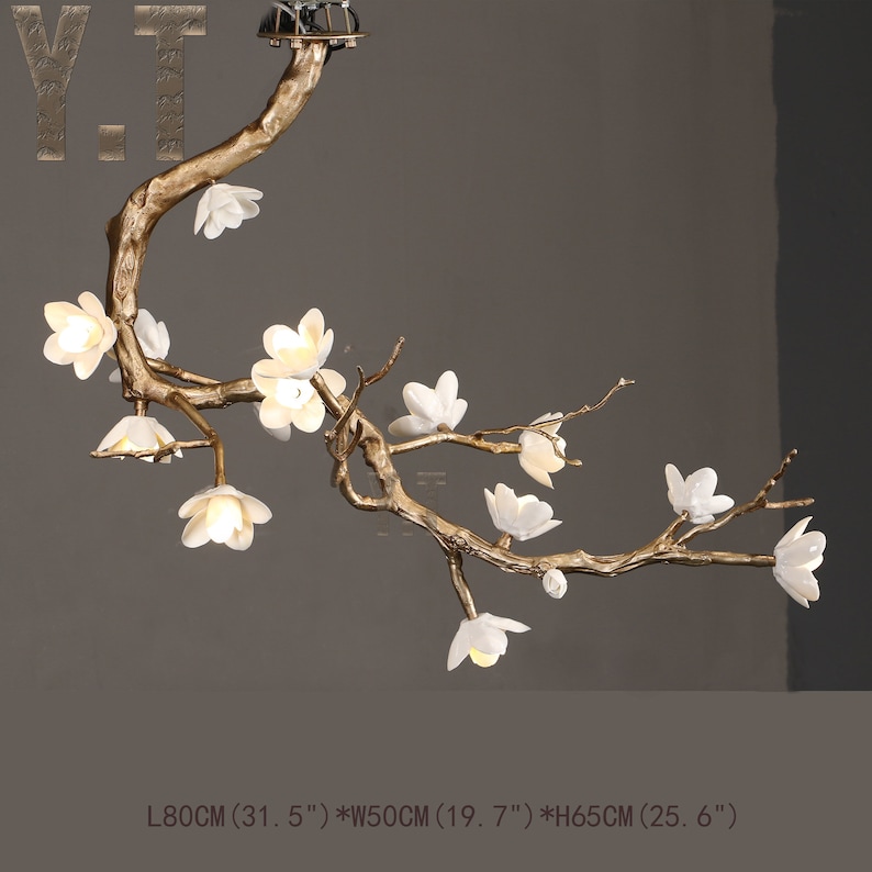 May include: A decorative chandelier in the shape of a flowering branch. The fixture has a gold-colored metal frame with white flower-shaped lights. The dimensions are approximately 31.5 inches long, 19.7 inches wide, and 25.6 inches high.