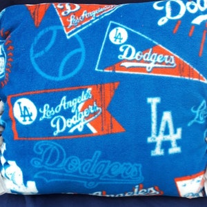 May include: Blue and red Los Angeles Dodgers themed pillow with a baseball, the team's logo, and the words "Los Angeles Dodgers" repeated throughout.