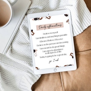 May include: A digital tablet displaying a white background with brown abstract shapes and text that reads "Daily affirmations". The text includes positive affirmations such as "I believe in myself" and "I am limitless and anything is possible".