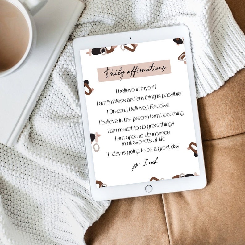 May include: A digital tablet displaying a white background with brown abstract shapes and text that reads "Daily affirmations". The text includes positive affirmations such as "I believe in myself" and "I am limitless and anything is possible".
