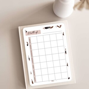 May include: A printable monthly calendar planner with a white background and black grid lines. The calendar has a pink header with the text "Month of:" and a brown and black abstract design on the border.