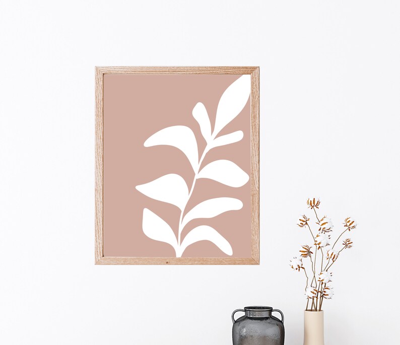 May include: A framed print featuring a white stylised leaf design on a light pink background.
