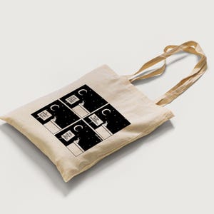 Può includere: Una borsa tote beige con illustrazioni in bianco e nero di una persona che tiene un cartello con su scritto "Ne ho abbastanza" in stile fumetto. La borsa ha un manico lungo.