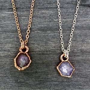 May include: Two delicate necklaces with a purple gemstone pendant. The necklaces are made of silver and rose gold chains.
