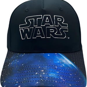 May include: A black baseball cap with a white "Star Wars" logo on the front. The cap has a blue and white galaxy print on the underside of the brim.