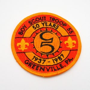 May include: A round, orange and yellow Boy Scout Troop 55 patch. The patch features the text "Boy Scout Troop 55" and "50 Years" in a circular pattern. The center has a large "5" and the years "1937-1987".