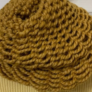 Könnte beinhalten: Ein dicker, grob gestrickter Schal mit Schalkragen in Senfgelb. Der Schal ist aus weichem, flauschigem Garn gefertigt und perfekt, um sich im Winter warm zu halten.