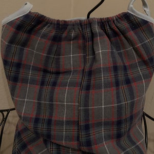 May include: A gray plaid fabric with red, blue, and yellow stripes. The fabric is gathered at the top and has a light blue trim.