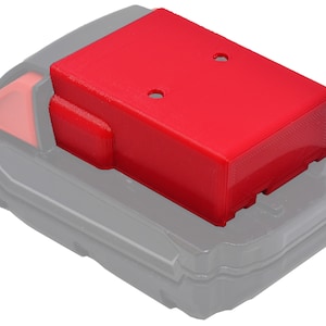 May include: Red plastic battery adapter for a power tool. The adapter has two holes on top and fits on top of a black battery.