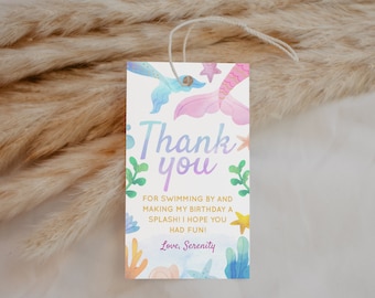 May include: A thank you tag with a mermaid tail and starfish design. The tag is white with a pink, blue, and purple watercolor background. The text on the tag reads "Thank you" in a purple and blue font. The text below reads "For swimming by and making my birthday a splash! I hope you had fun! Love, Serenity".