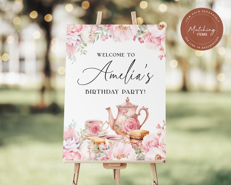 May include: A white sign with pink floral designs and a teapot and teacups. The sign says "Welcome to Amelia's Birthday Party!"