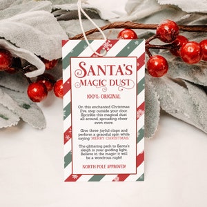 Puede incluir: Una etiqueta de regalo con temática navideña con el texto "SANTA'S MAGIC DUST". La etiqueta tiene un borde a rayas rojas y verdes e incluye instrucciones de uso. La etiqueta es blanca con detalles en rojo y verde y una cuerda para colgar.