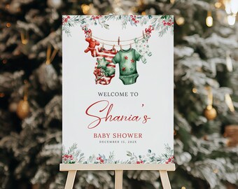 May include: A white sign with a green and red watercolor design of baby clothes hanging on a clothesline. The sign says "Welcome to Shania's Baby Shower December 13, 202X".